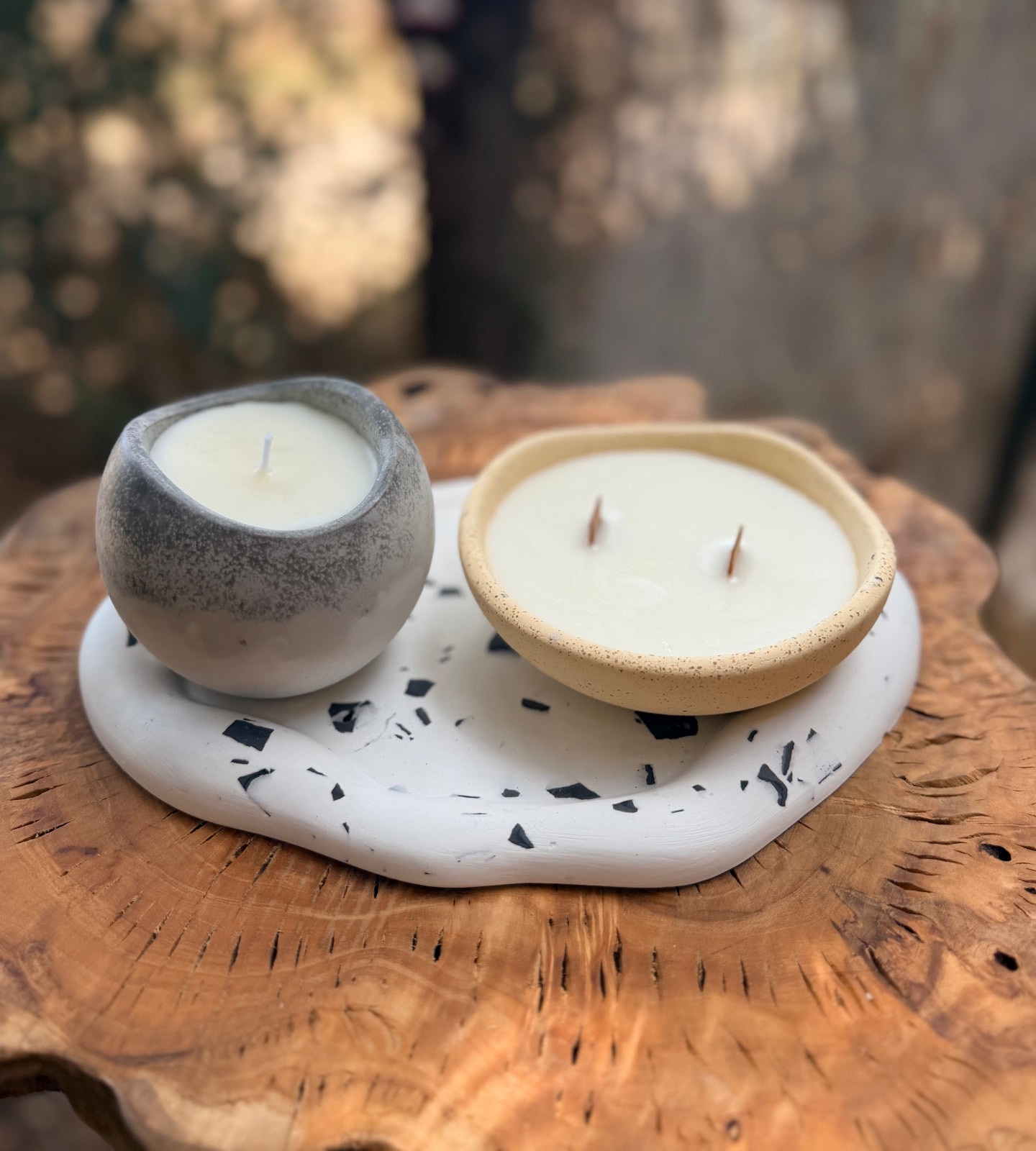 שני נרות ארומתרפיים על מגש טרצו גלי מעל פרוסת עץ